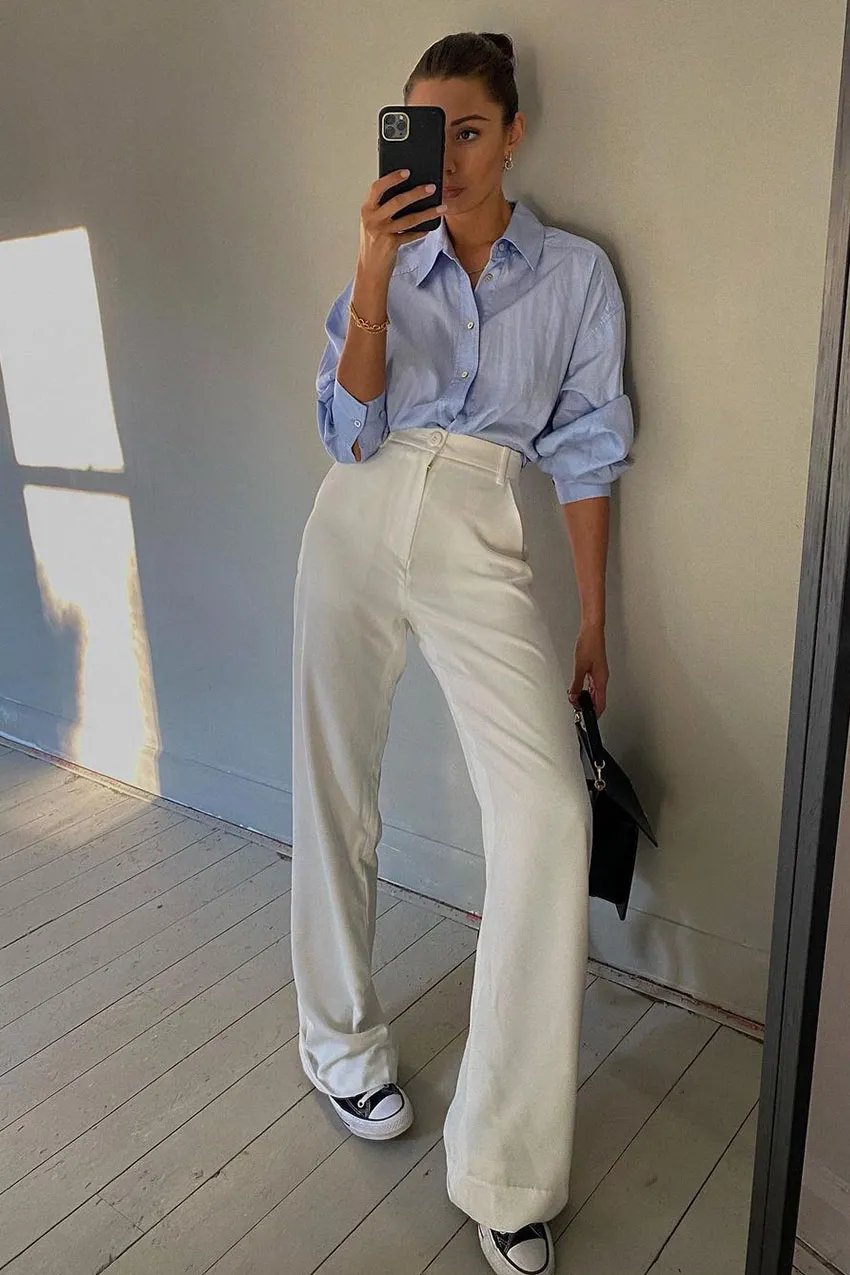 Chic summer outfit with white wide-leg pants a blue button-up shirt and Converse sneakers